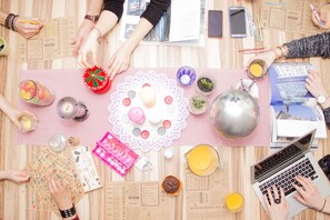 A table with various items including a laptop, a mobile phone, a notebook, and a placemat with a doily.