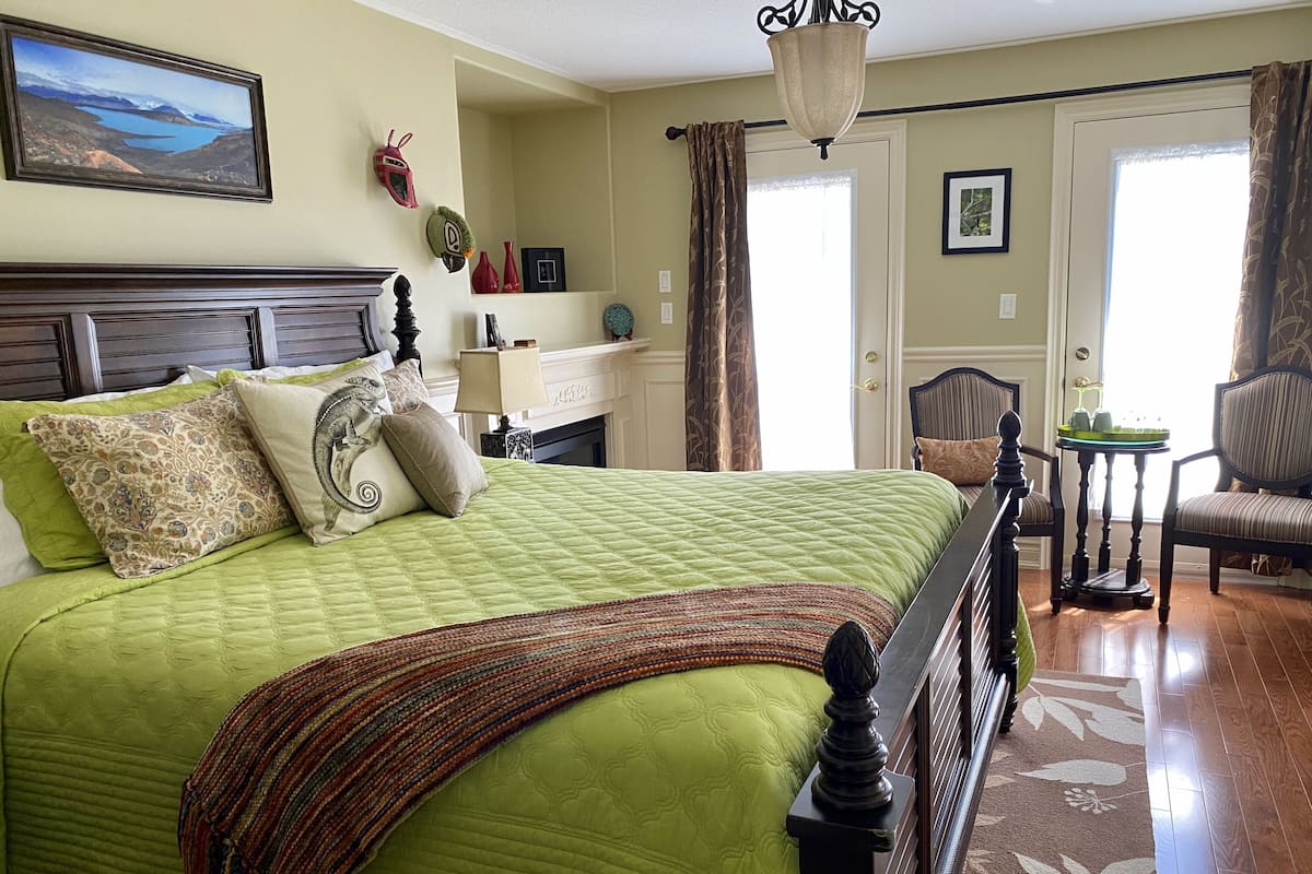 A well-appointed bedroom with a large bed, a dresser, a chair, and a fireplace.