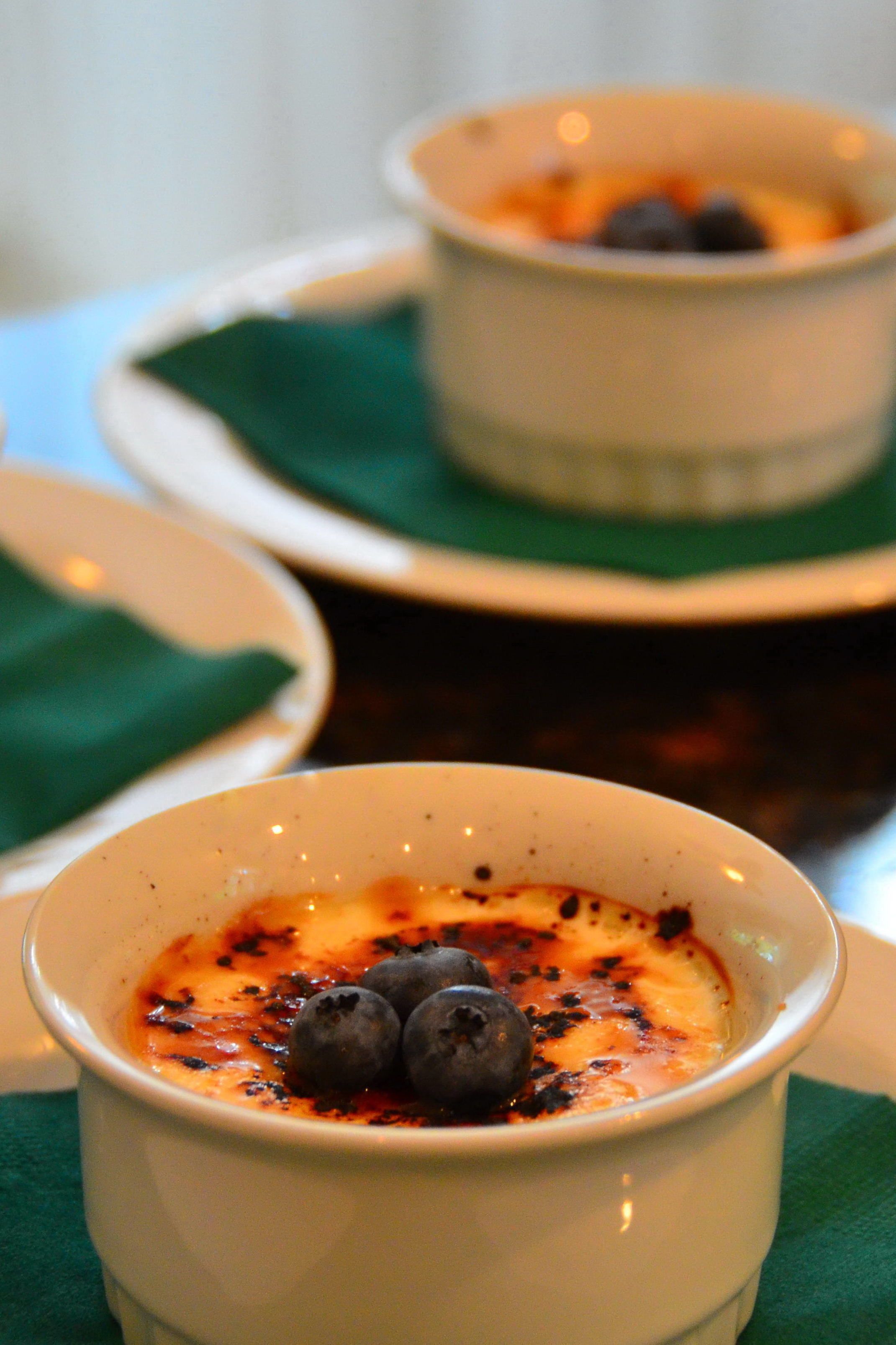 A dessert dish with a creamy topping and blueberries, served on a white plate with a green napkin underneath.