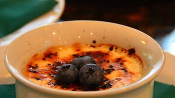 A dessert dish with a creamy topping and blueberries, served on a white plate with a green napkin underneath.