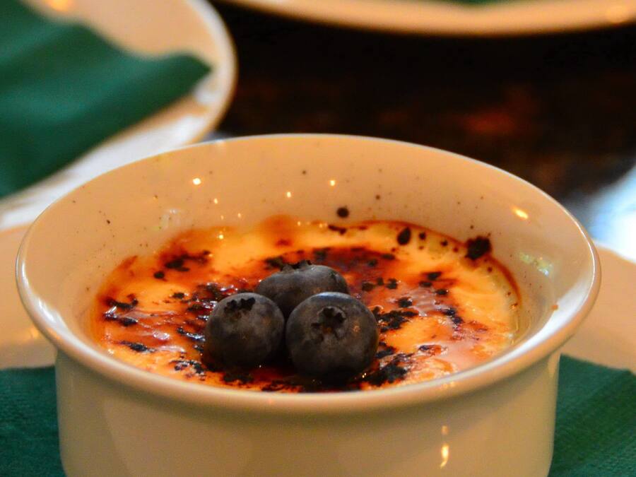 A dessert dish with a creamy topping and blueberries, served on a white plate with a green napkin underneath.