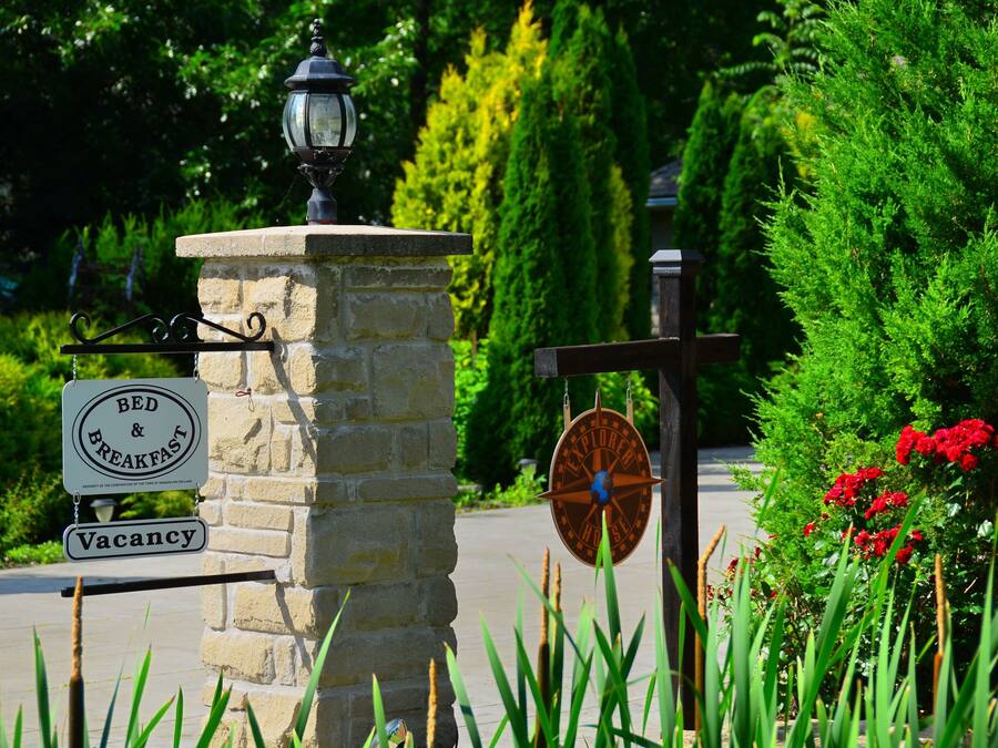 A stone pillar with a sign indicating a bed and breakfast, a vintage lantern, and a compass sign.