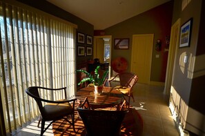 A dining area with a round glass table, chairs, and a potted plant. - Explorer House (Niagara-on-the-Lake)