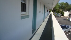 A long corridor of a hotel with white walls and teal doors, leading to individual rooms. - Budget Inn Motel Suites (Somers Point)