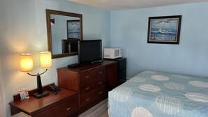 A hotel room with a bed, a dresser, a television, a microwave, and a mirror. - Budget Inn Motel Suites (Somers Point)