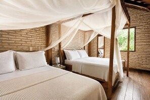 Una habitación con dos camas, un muro de ladrillo y suelo de madera.