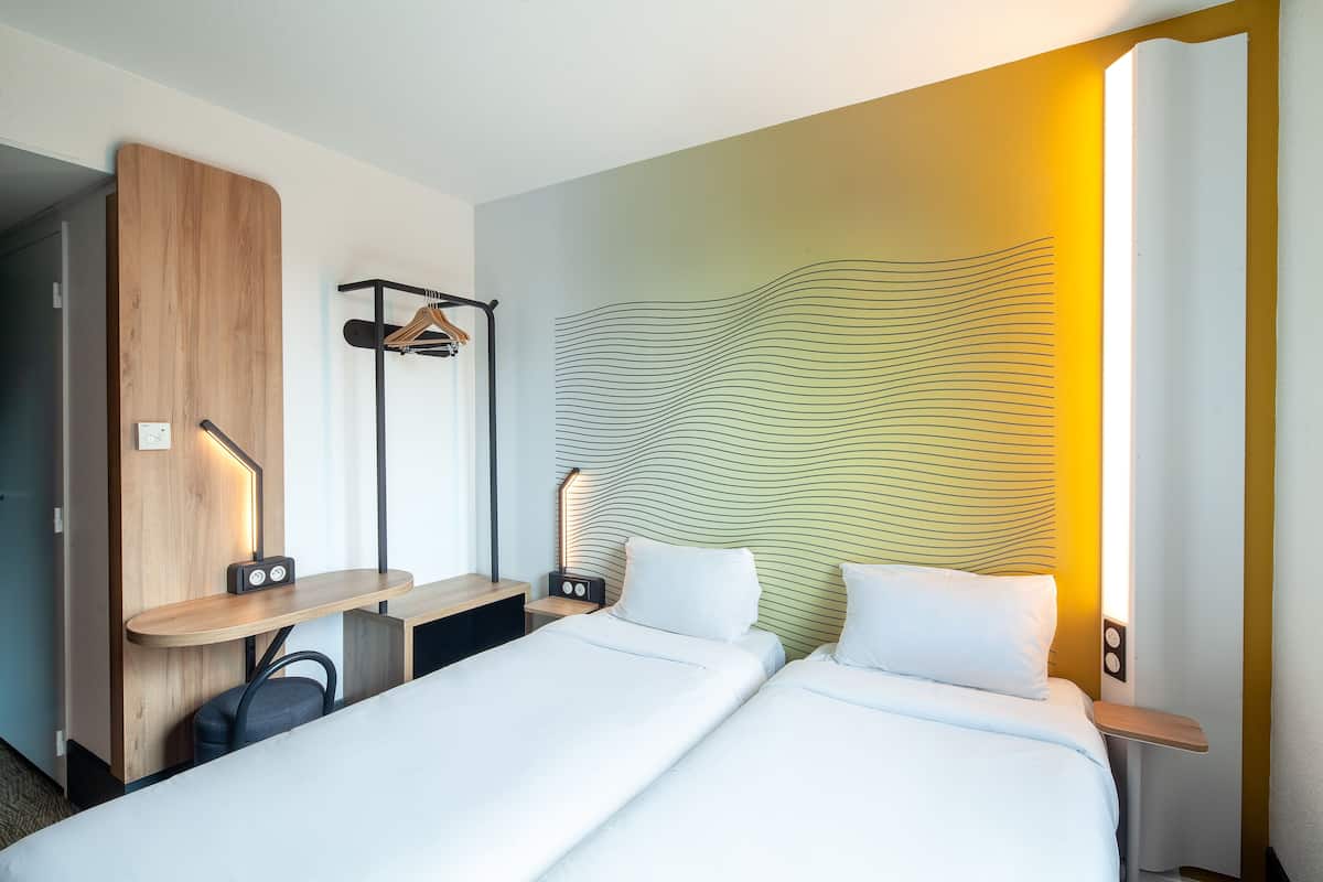 Een hotelkamer met een bed, nachtkastjes, een bureau, een stoel en een kapstok.