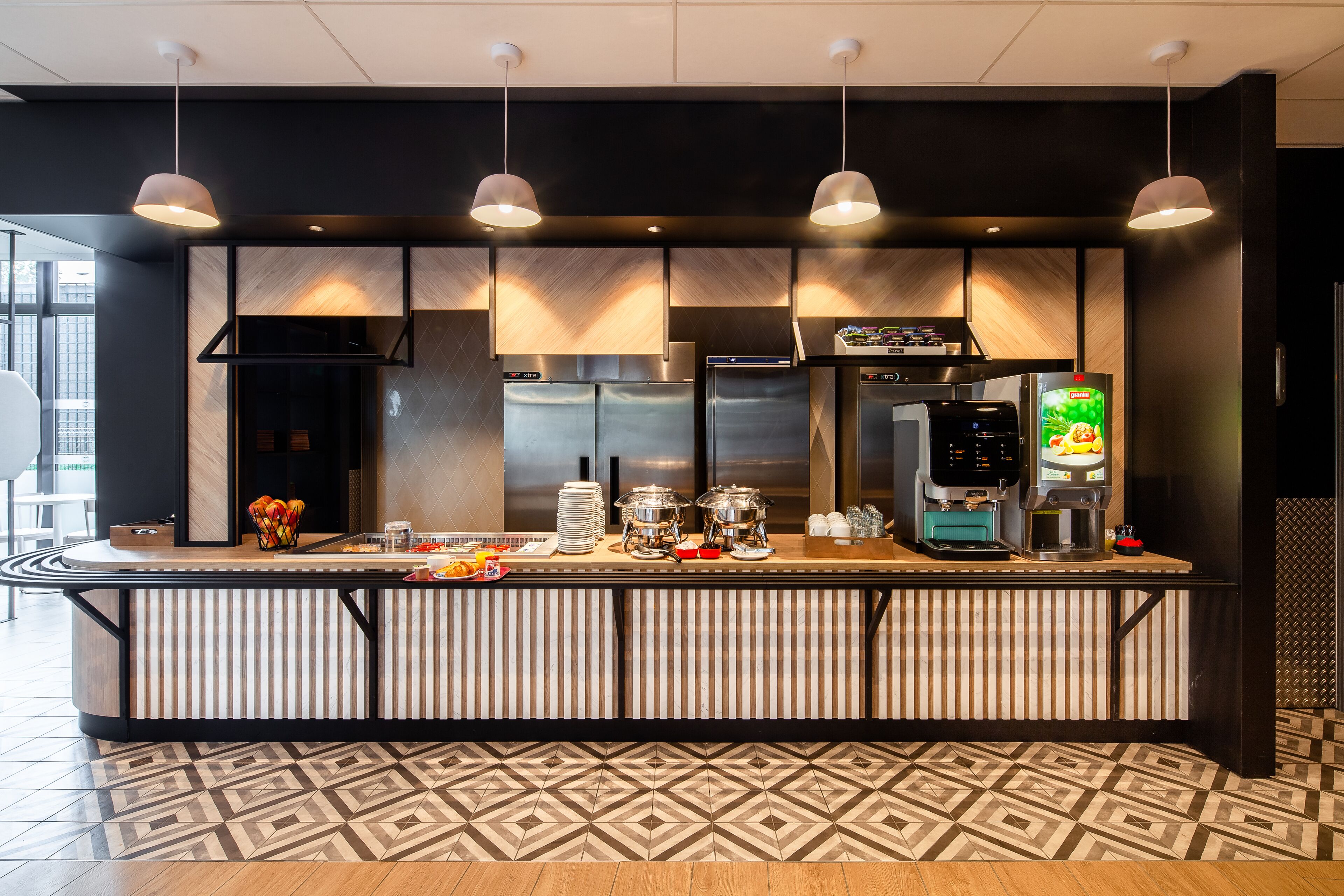 A modern kitchen with a central island, stainless steel appliances, and hanging pendant lights.