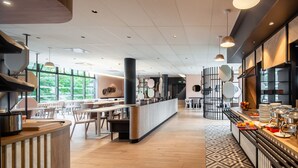 Een modern restaurant met een lange toonbank, een zithoek en grote ramen.