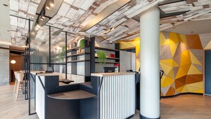 A modern reception area with a wooden reception desk, a seating area with chairs, and a geometric patterned wall.