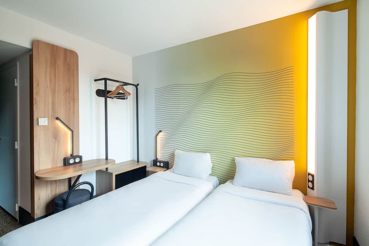 Een hotelkamer met een bed, een bureau, een stoel, een kapstok en een muur met een golvend patroon.
