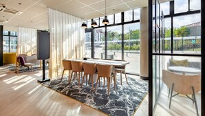 A modern dining area with a marble floor, a table with chairs, and large windows offering a view of the outdoors.