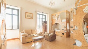 A spacious living room with a sofa, armchair, and a wooden wall with built-in shelves.