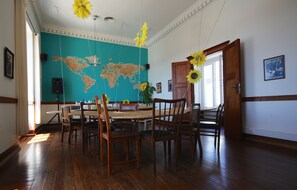 A dining room with a wooden table and chairs, a world map on the wall, and a door with a poster.