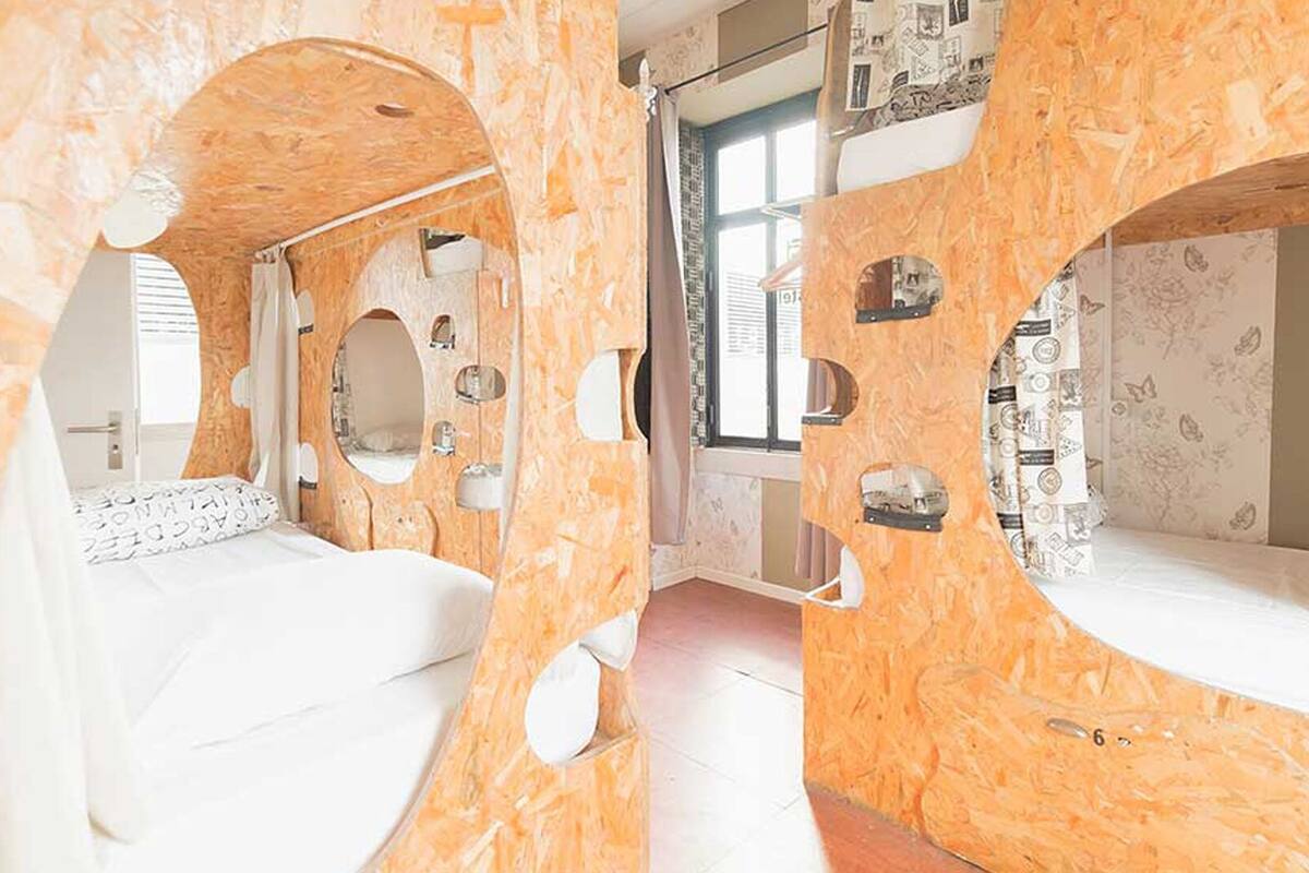 A room with a unique wooden design, a bed, a window, and a mirror.