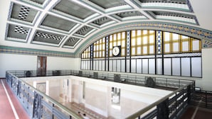 A spacious hall with a high ceiling, ornate railings, and a large clock on the wall. - Sunset Destination Hostel (Lisbon)