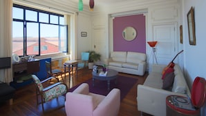 A living room with a sofa, armchairs, a coffee table, and a TV. - Sunset Destination Hostel (Lisbon)
