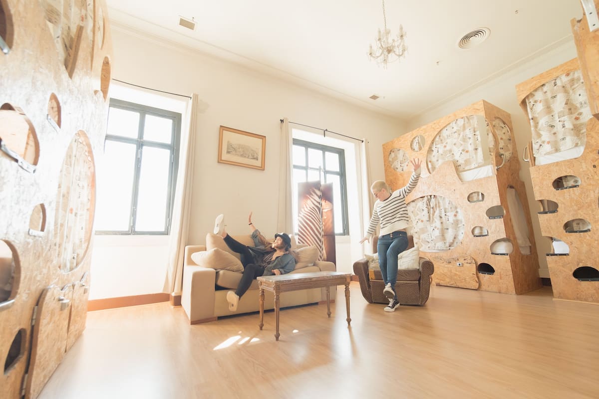 A spacious living room with a large window, a wooden floor, and a unique play structure with multiple levels and tunnels.