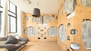 A modern room with a unique wooden wall design, a sofa, and a hanging light fixture. - Sunset Destination Hostel (Lisbon)