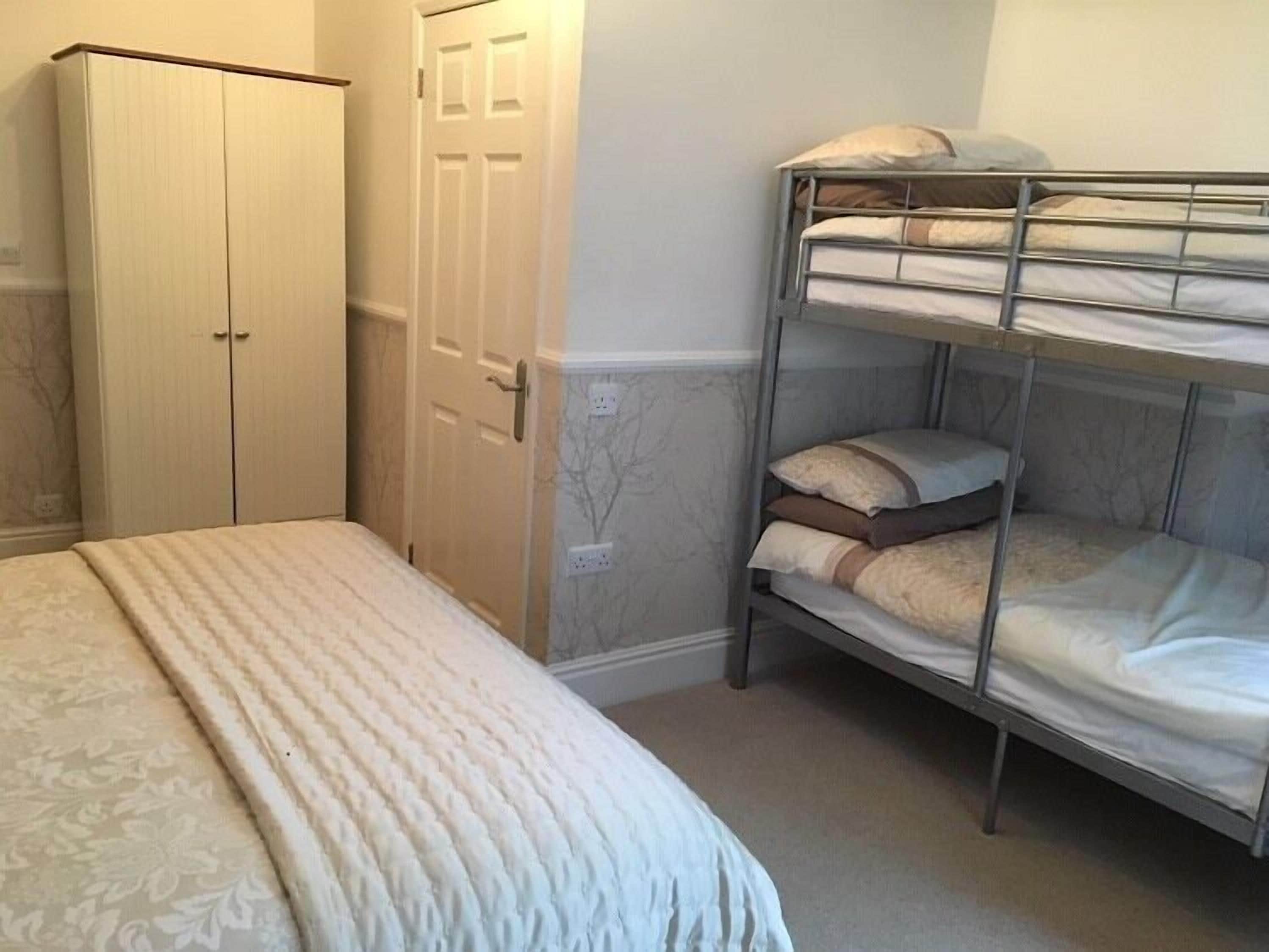 A bedroom with a bunk bed, a wardrobe, and a patterned bedspread.