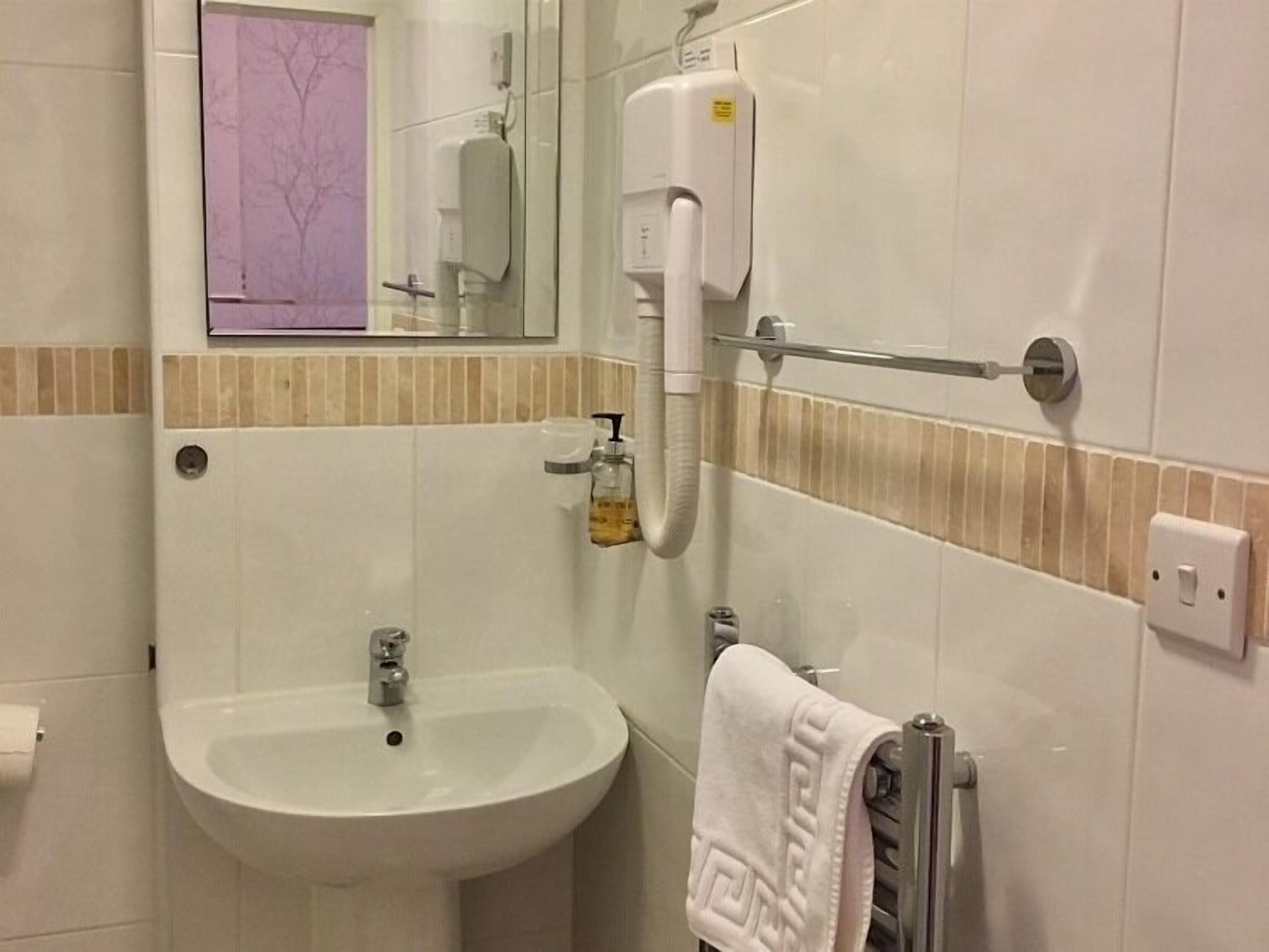A bathroom with a sink, a mirror, a towel rack, and a hand dryer.