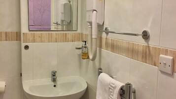 A bathroom with a sink, a mirror, a towel rack, and a hand dryer.