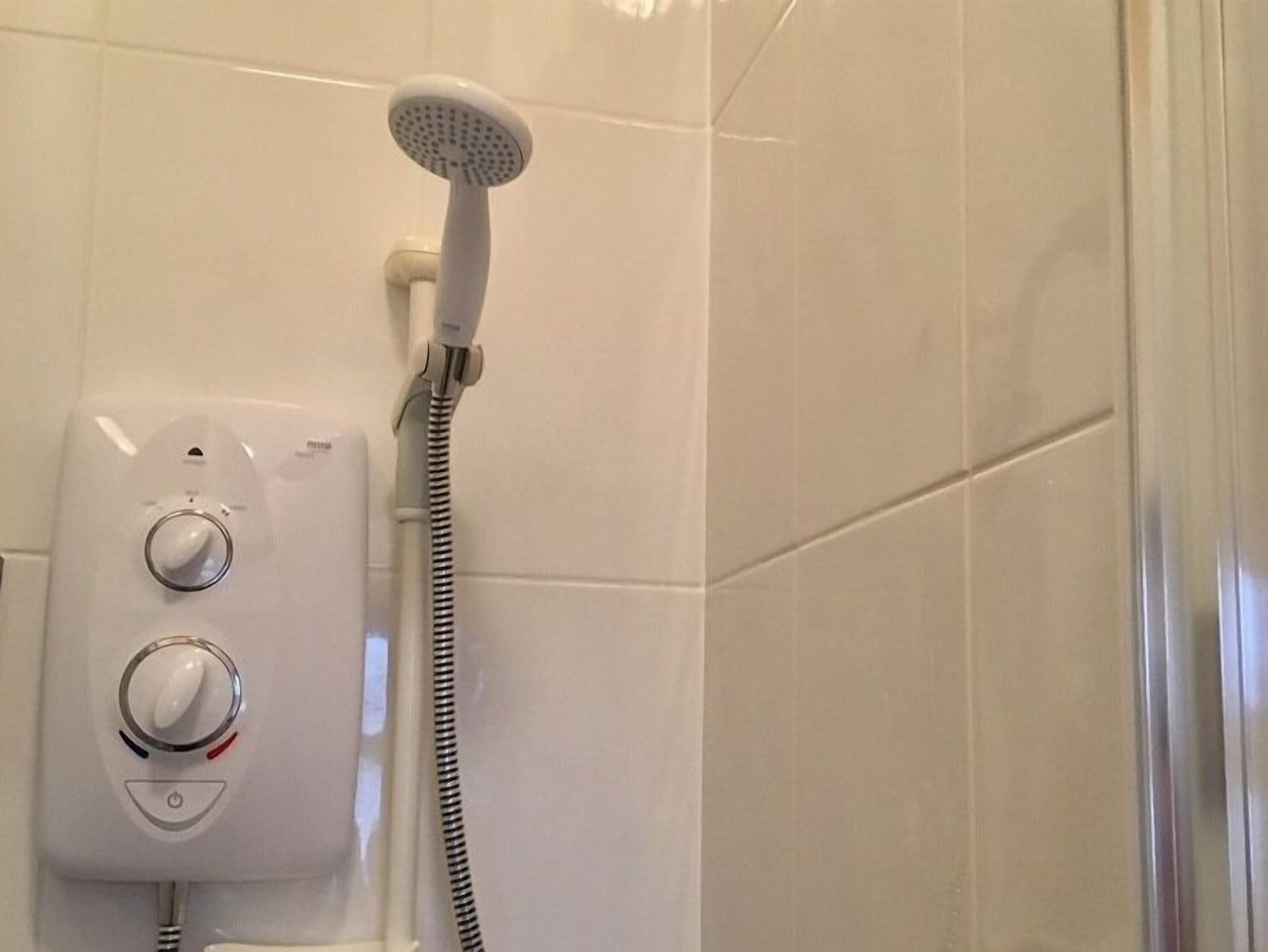 Une douche équipée d’un pommeau de douche à main et de boutons de commande.
