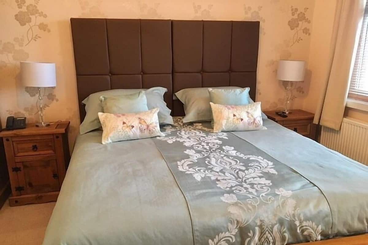 A bedroom with a large bed, two bedside tables, and a nightstand with a lamp.