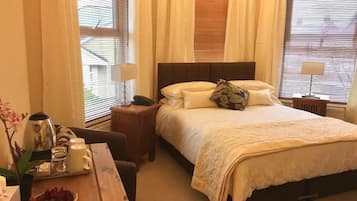 Een hotelkamer met een bed, nachtkastjes, een bureau met lamp en een raam met zonwering.