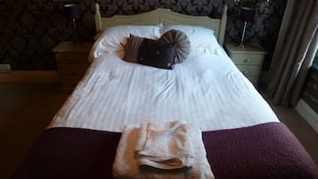 Cama bem arrumada com uma toalha dobrada e um travesseiro decorativo.