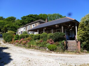 A two-story stone house with a covered porch and a gravel driveway.