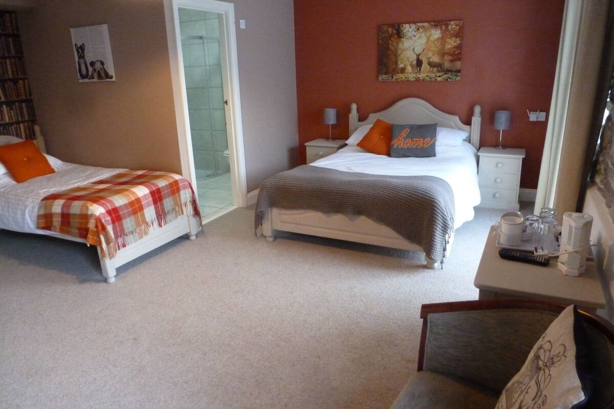 A hotel room with two beds, a desk with a coffee maker, and a painting on the wall.
