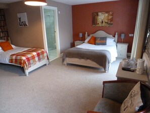 A hotel room with two beds, a desk with a coffee maker, and a painting on the wall.