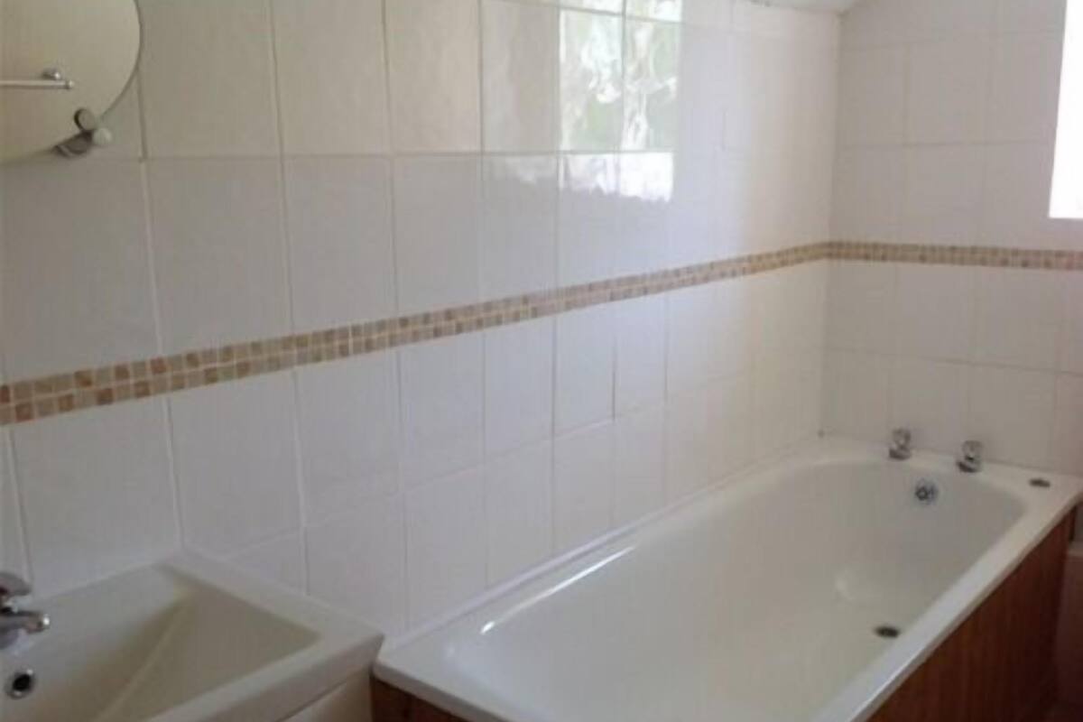 A bathroom with white tiles, a bathtub, and a sink.
