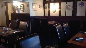 L’intérieur d’un restaurant, avec des banquettes, des tables et un plafond en bois.