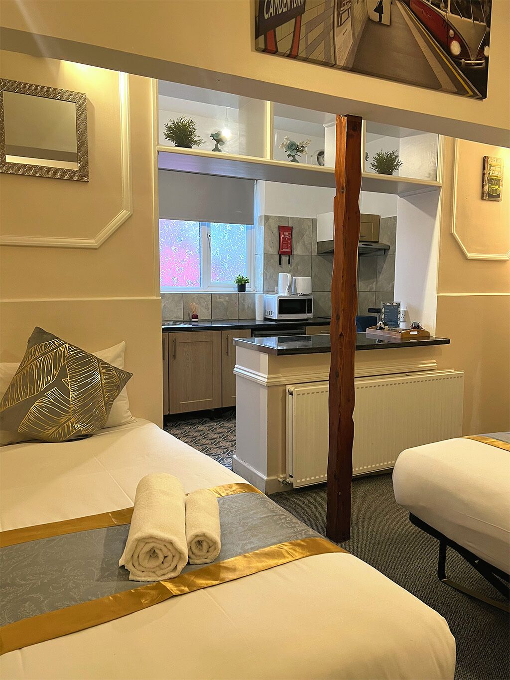 Quarto de hotel com duas camas, uma kitchenette e vista para a rua.