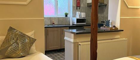 Quarto de hotel com duas camas, uma kitchenette e vista para a rua.