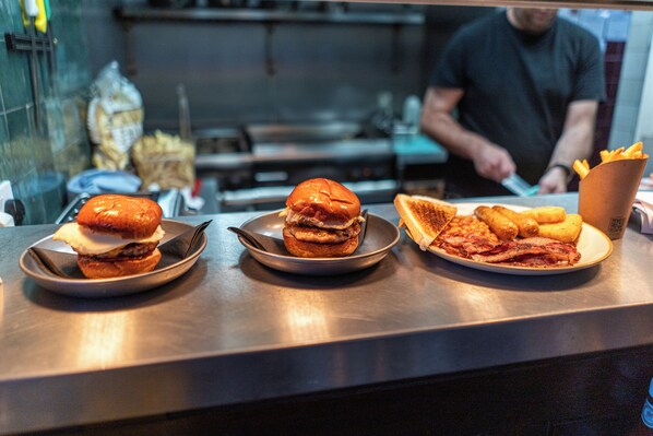 A counter with three plates of food, including burgers and fries.