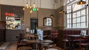 A cozy restaurant with wooden furniture, a pizza sign, and a sign for toilets and hostel. - PubLove The White Ferry, Victoria - Hostel (London)