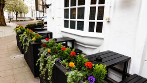 Outdoor seating with black benches and flower planters along a white building. - PubLove The White Ferry, Victoria - Hostel (London)