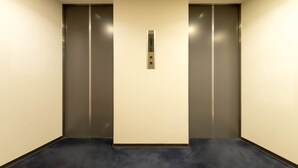 A modern elevator with a control panel in a hallway with dark flooring and light walls. - Hotel Matsunoka Ichinoseki (Ichinoseki)