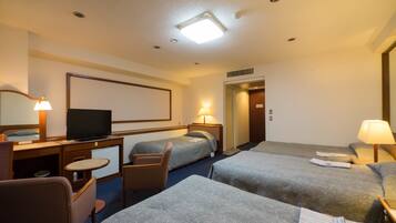 A hotel room with two beds, a desk with a television, a chair, and a desk lamp.