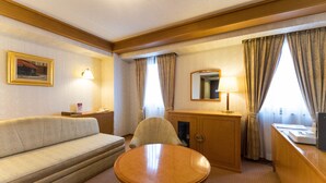 A hotel room with a sofa, a round table, a desk with a mirror, and curtains. - Hotel Matsunoka Ichinoseki (Ichinoseki)