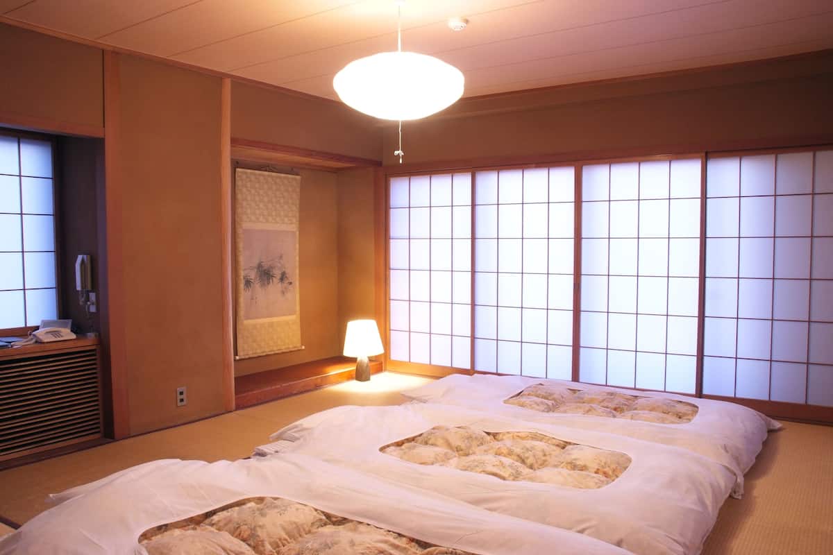 Ein traditioneller japanischer Raum mit Tatami-Bodenbelägen, Shoji-Schirmen und einem Futonbett.