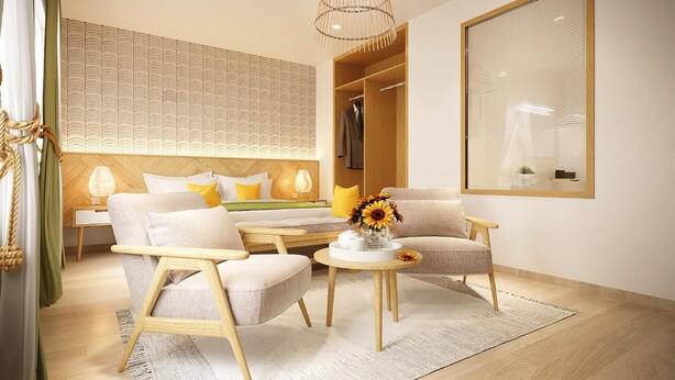 A modern hotel room with a bed, a sofa, two armchairs, a small table with a vase of flowers, a large mirror, and a wardrobe. - The Pearl Hotel (Hanoi)