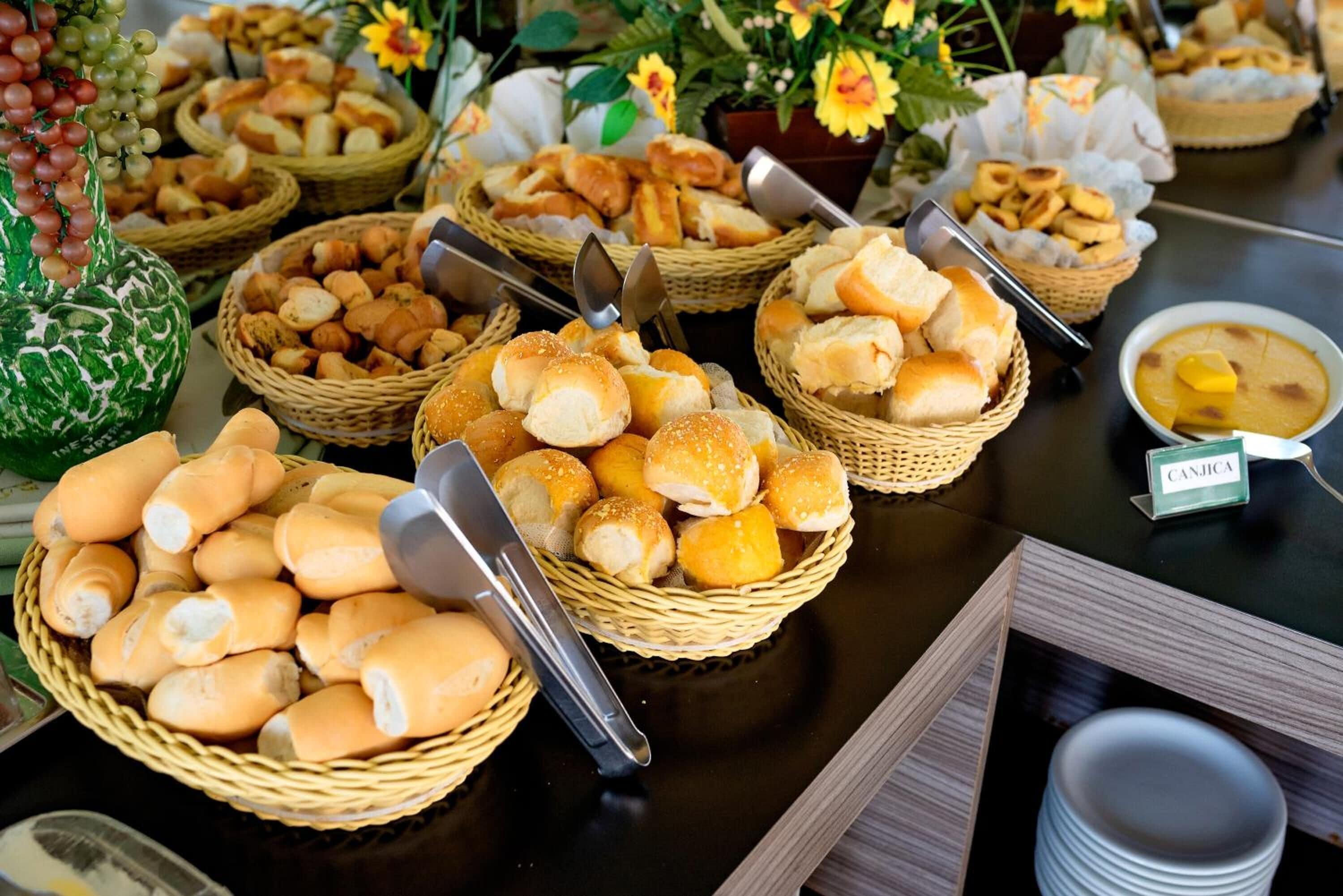 A buffet table with various food items in baskets, including bread rolls and pastries.