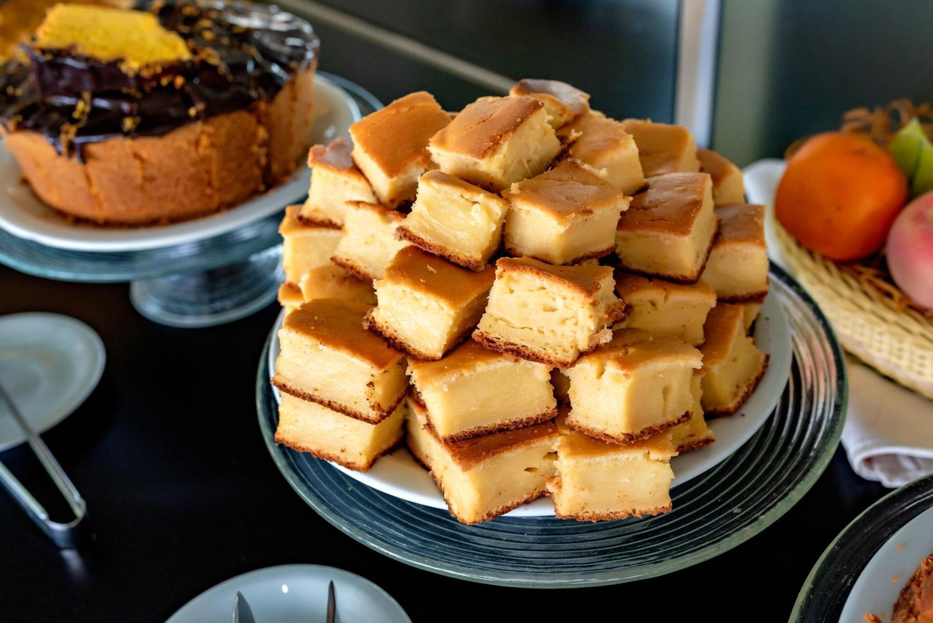 Une pile de petits morceaux de dessert de forme carrée, de couleur caramel, disposés sur une assiette en verre.