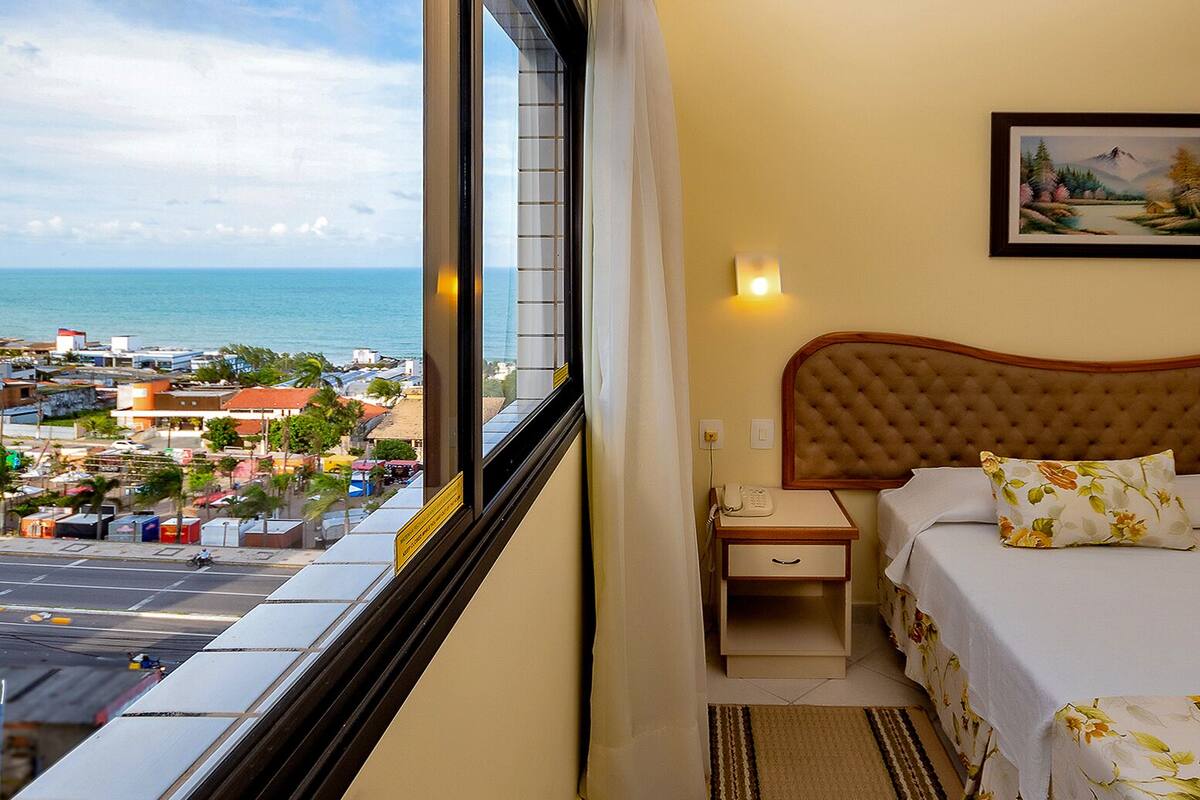 A hotel room with a bed, a nightstand, a telephone, and a painting on the wall.