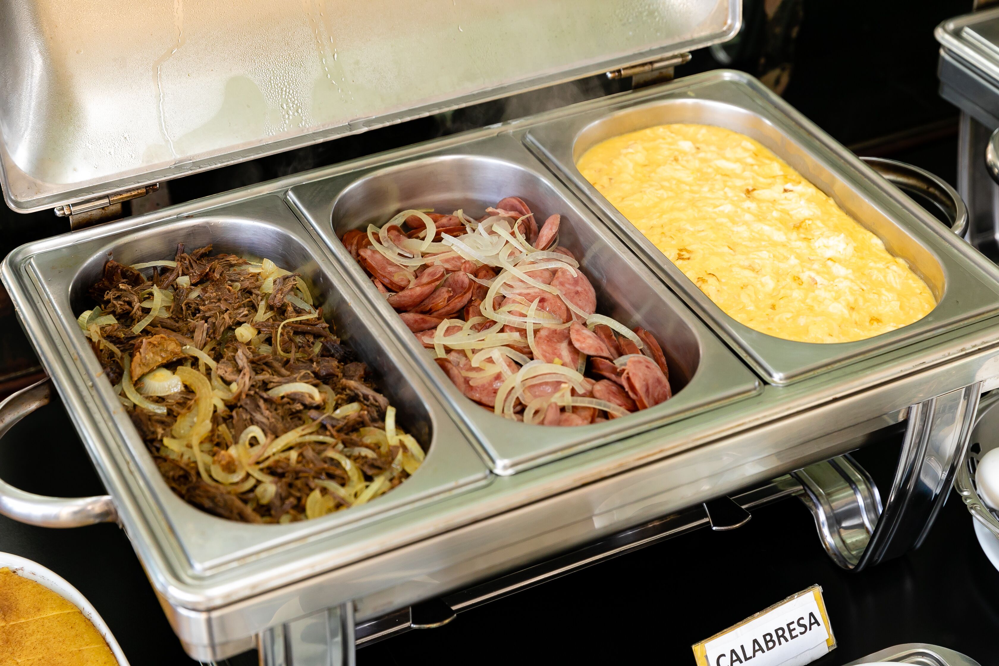 A buffet with various food options including a dish labeled 'CALABRESA'.