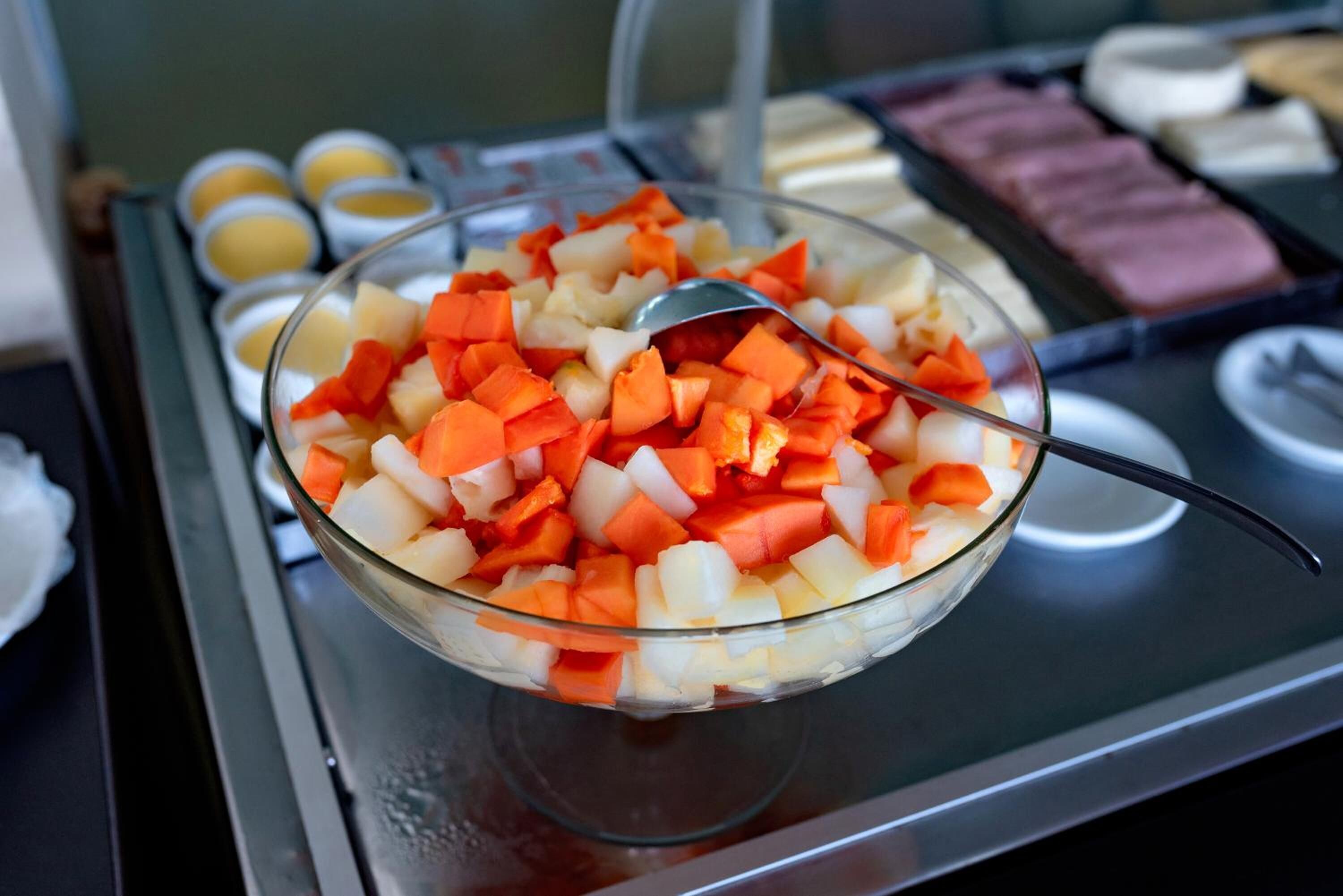 Un bufé con una variedad de alimentos, incluyendo un tazón de vegetales picados.